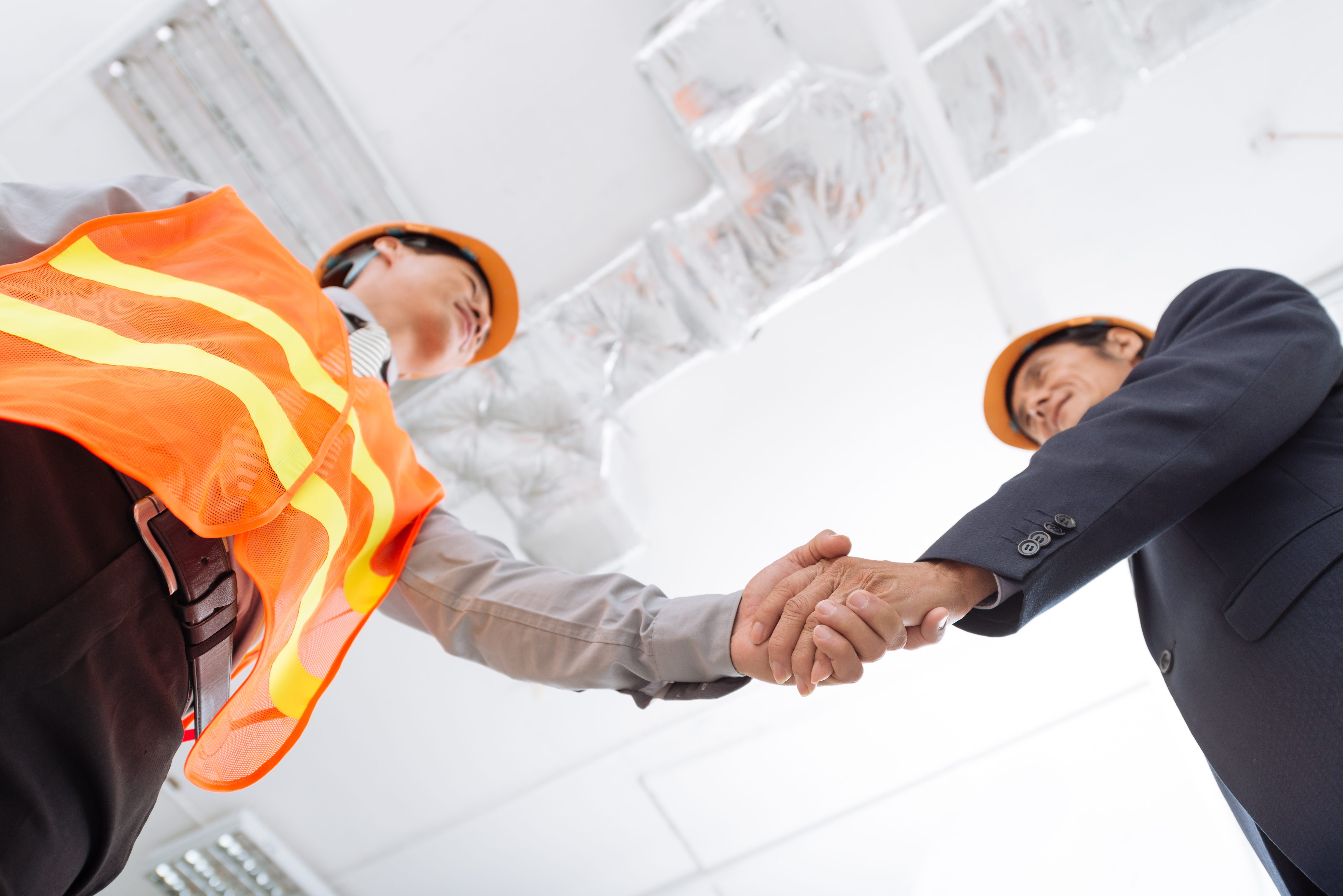 Two men wearing hard hats shaking hand