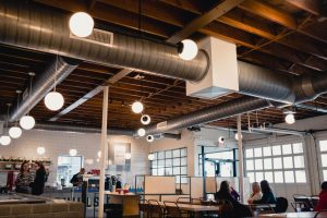 Commercial HVAC ductwork providing ventilation in a modern café interior